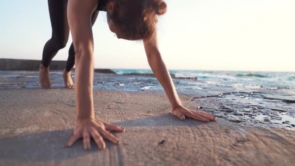 年轻女子卷曲的头发在黑色服装练习瑜伽在日出光，简约的场景。做阿萨娜健康的生活方式理念. — 图库视频影像