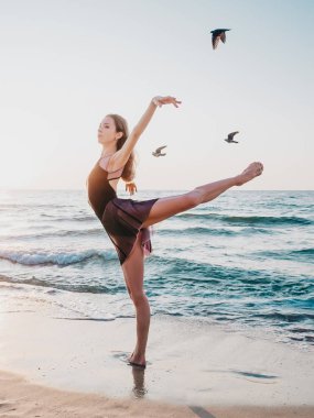 Güzel jimnastikçi veya balerin sabah deniz arka plan ve uçan kuşlar üzerinde uzanan gösteren. İnanılmaz bir sahne. Doğa, bale, dans, özgürlük kavramı