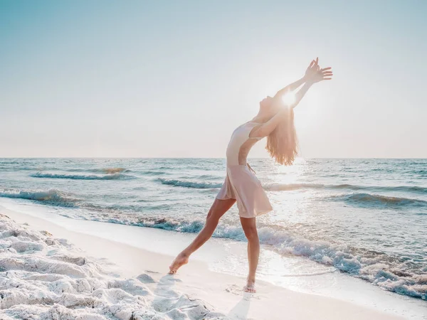 Karcsú szép balerina fehér ruhában táncoló balett a tengeren, vagy óceán homokos tengerpart a reggeli fényben. A művészet fogalma, természetszépség — Stock Fotó