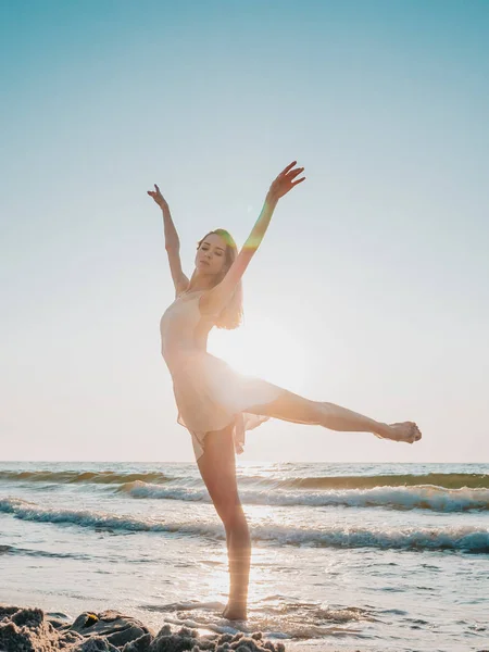 Bailarina bonita esbelta no balé de dança vestido branco no mar ou praia de areia do oceano na luz da manhã. Conceito de arte, beleza da natureza — Fotografia de Stock