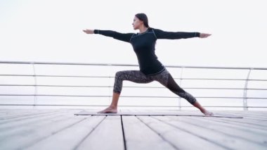 Siyah güzel kız ahşap sahilde yoga yapıyor. Dolly atış. 
