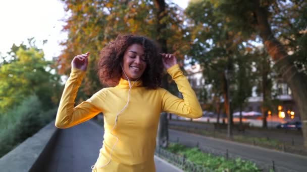 Renkli sarı elbiseli hippi sonbahar şehir caddesinde yürüyor ve dans ediyor.. — Stok video