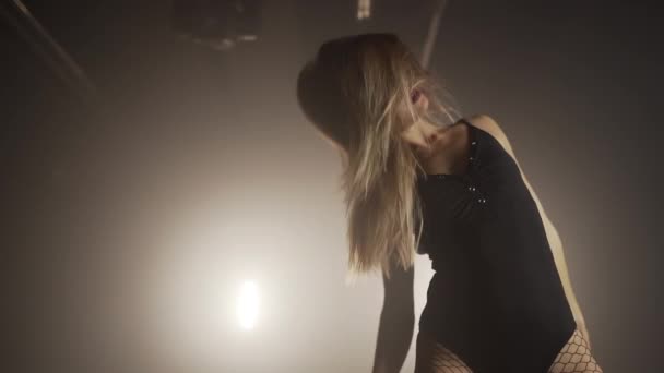 Mujer joven en traje de cuerpo negro con pantimedias netas se mueve plácidamente a la música en la habitación oscura.Concepto de baile sexual, coreografía, arte . — Vídeo de stock