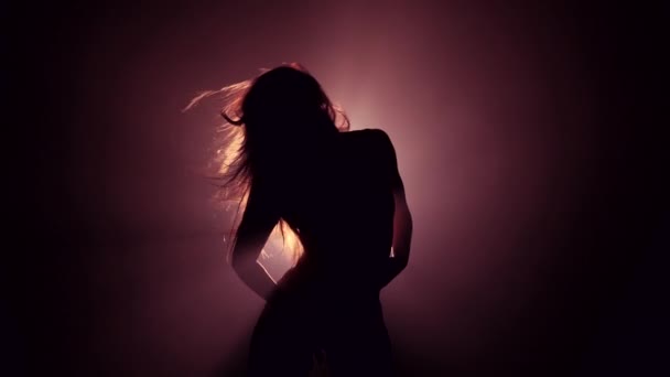 Silhouette de belle danseuse sur fond sombre fumé.Projecteur brille de retour contre fille sexy. Elle bouge séduisante . — Video