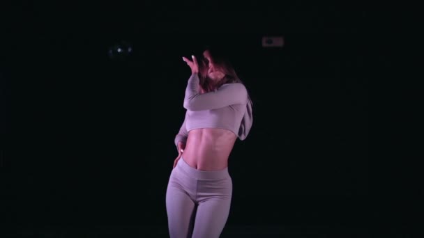 Portrét krásné dívky v růžovém přiléhavém obleku smyslně tančící v tmavém ateliéru s fialovými lampami.Koncept choreografie, tance, performance — Stock video