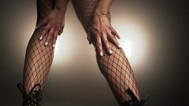 Junge Tänzerin passt mit den Händen ihre Netzstrumpfhose an Beine in Absätzen an. Frau streichelt ihren sexy Körper. Lady in Smoke Scheinwerfer auf der Bühne. Zeitlupe. — Stockvideo