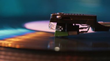 Görüntü yönetmeni vinil plak çalar ve müzik plakası boyunca uzanan bir pikap. Neon ışığı. Retro-stil dönen plak çalar. Kapat.