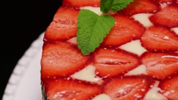 Incroyable belle main décorée maison fraise gâteau Fraisier tourne. Savoureux, frais, appétissant dessert gros plan avec des brins de menthe. Art de la confiserie, perfectionnisme dans le concept alimentaire. — Video