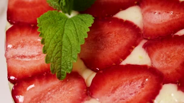 漂亮的手装饰精美的自制草莓蛋糕旋转。美味，新鲜，开胃的甜点特写与薄荷小枝。食品观念中的精品艺术、完美主义. — 图库视频影像
