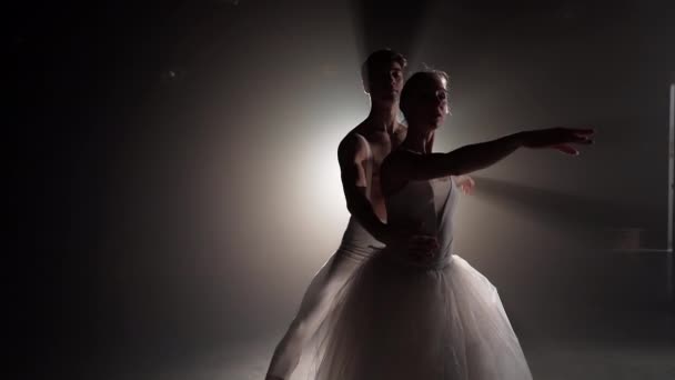 Casal de balé profissional dançando em holofotes fumam em grande palco. Mulher bonita e homem em holofotes fundo. Dueto emocional realizando arte coreográfica. Movimento lento — Vídeo de Stock