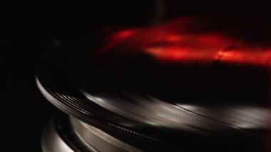 Görüntü yönetmeni vinil plak çalar ve müzik plakası boyunca uzanan bir pikap. Neon ışığı. Retro-stil dönen plak çalar. Kapat.