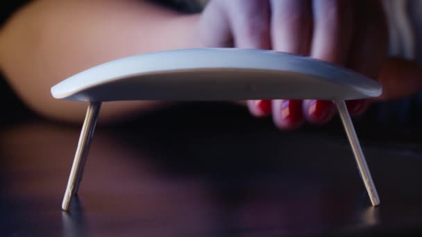 La mujer pinta las uñas con esmalte de gel rojo solo en casa. Uv llevó la lámpara para secar la manicura. Método moderno de trabajo con las manos. Instrumento ultravioleta, equipo maestro. 4k — Vídeo de stock