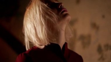 Güzel, çekici bir kız zevk alır, saçlarına ve yüzüne dokunur. Siyah arka planda sarı saçlı seksi bir kadının portresi. Geceleri şehirde müzik. Burun delici. Yavaş çekim.
