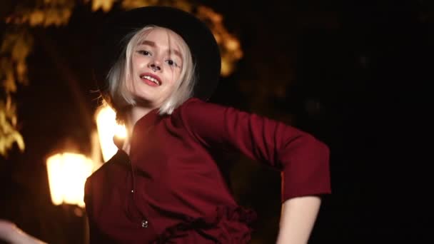 Femme hipster millénaire avec coiffure blonde dansant sous la lanterne de la rue de la ville la nuit. Chapeau, piercing du nez. Drôle de fille. Mouvement lent. — Video