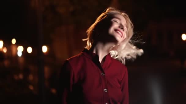 Portrait de femme hipster millénaire avec coiffure blonde fait des visages drôles, s'amuser autour. Rue de la ville la nuit. Chapeau, piercing du nez. Drôle de fille. Mouvement lent. — Video