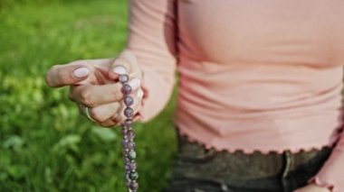 Doğada dua eden genç bir kadın eli dua etmek ve dua etmek ve meditasyona konsantre olmak için tespih kullanır. Din, umut, aşk konsepti. Yavaş çekim.