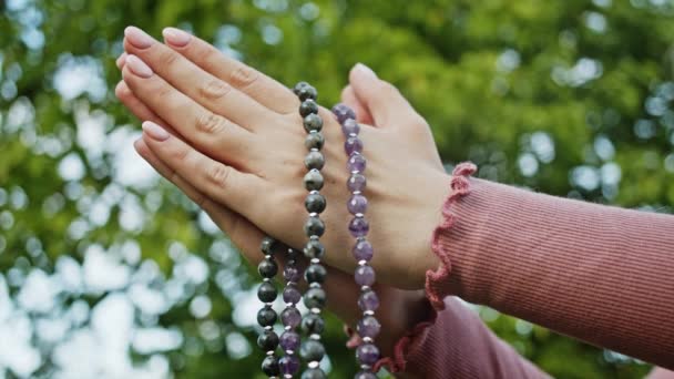 Mãos femininas com contas mala ou rosário juntos simbolizando oração e gratidão. Mudra. Conceito de ioga. Menina concentrada de pé com as mãos em namaste e meditando ou orando . — Vídeo de Stock