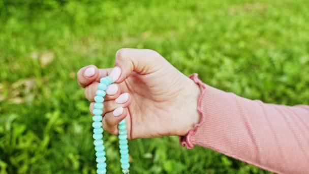 Hand unga troende kvinna ber i naturen och använder hantverk radband pärlor för att räkna bön och koncentrera sig på meditation. Religion, hopp, kärlek. Långsamma rörelser. — Stockvideo