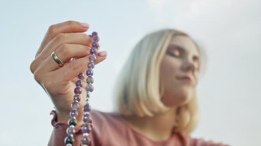 Doğada dua eden genç bir kadın eli dua etmek ve dua etmek ve meditasyona konsantre olmak için tespih kullanır. Din, umut, aşk konsepti. Yavaş çekim.
