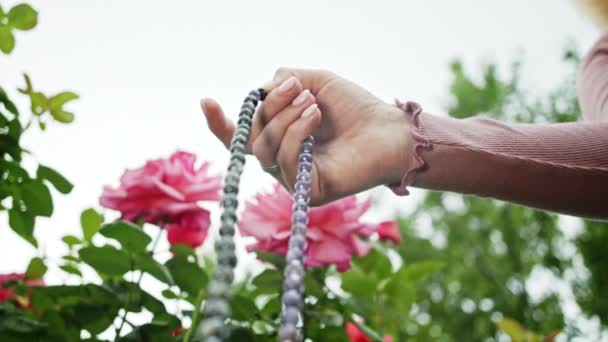 Frau zündete Hand in Großaufnahme zählt Rosenkranz - malas Stränge von Edelsteinen Perlen verwendet, um Zählung während Mantra-Meditationen zu halten. Mädchen sitzt auf der Sommernatur. Zeitlupe. — Stockvideo