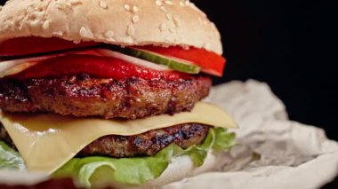 Lezzetli hamburger, fast food konsepti. Et köftesi, domates, salatalık, marul, soğan ve susamlı taze ev yapımı ızgara burger. Sağlıksız bir yaşam tarzı. Yemek arkaplanı. 4k