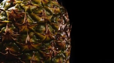 Siyah arka planda dönen sulu, taze bir ananas. Meyve izole edilmiş. Tropikal ürünün makro yüzeyi. 4 bin. Yüksek kaliteli görüntüler.