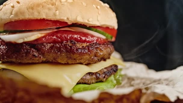 Finom hamburger, gyorskaja koncepció. Friss házi készítésű grillezett burger húspogácsával, paradicsommal, uborkával, salátával, hagymával és szezámmaggal. Egészségtelen életmód. Étel háttér. 4k — Stock videók