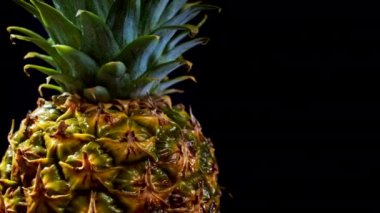 Siyah arka planda dönen sulu, taze bir ananas. Meyve izole edilmiş. Tropikal ürünün makro yüzeyi. 4 bin. Yüksek kaliteli görüntüler.