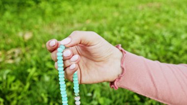 Elini yakan kadın tespihi de sayıyor. Mantra meditasyonları sırasında saymak için kullanılan değerli boncuk iplikleri. Kız yaz doğasında oturuyor.