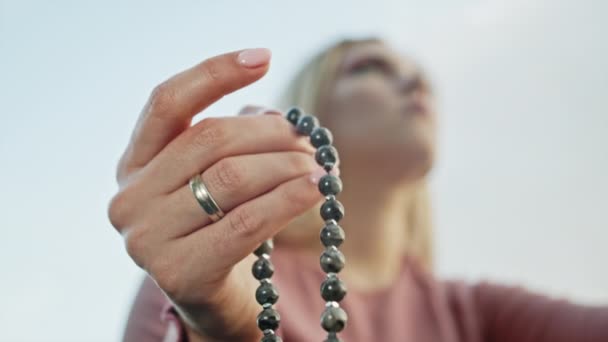 Mujer iluminada mano cerca cuenta rosario - malas hebras de piedras preciosas perlas utilizadas para mantener el recuento durante las meditaciones del mantra. Chica se sienta en la naturaleza de verano. Movimiento lento . — Vídeos de Stock