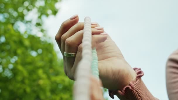 Mujer iluminada mano cerca cuenta rosario - malas hebras de piedras preciosas perlas utilizadas para mantener el recuento durante las meditaciones del mantra. Chica se sienta en la naturaleza de verano. Movimiento lento . — Vídeos de Stock