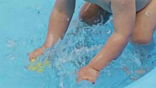 Childs mãos com patos de borracha amarela espirra água durante a natação na piscina ao ar livre no verão. Menino a divertir-se. Conceito de estilo de vida saudável, família, lazer no verão. Movimento lento . — Vídeo de Stock