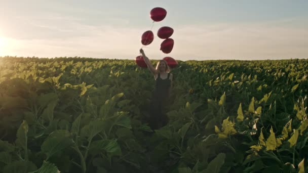 Attraktive Frau in femininem Midikleid, die Spaß mit herzförmigen Luftballons auf grünem Naturhintergrund hat. Sonnenuntergang Fackelschein. Geburtstagskind, Feiertag, Freiheitsfest. Zeitlupe — Stockvideo