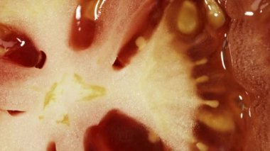 Domates diliminin makro görüntüsü. Dönüşümlü, soyut bir arka plan. Kırmızı sulu dokuya aşırı yakın çekim, sebzenin yapısı. Sağlıklı vejetaryen yemeği. 4k