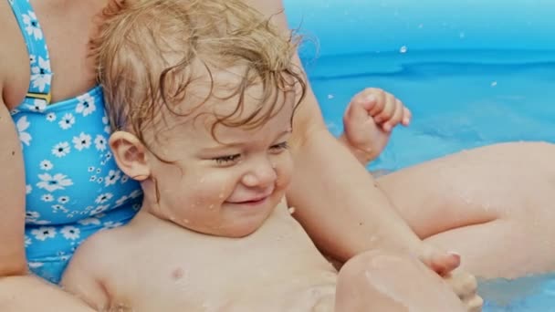 엄마는 파란 실외 수영장에서 작은 남자 애 랑 수영하고 있어요. 엄마와 아들은 웃으면서 즐거운 시간을 보냈습니다. 건강 한 생활, 가족, 여름 방학에 대한 개념. 느린 동작. — 비디오