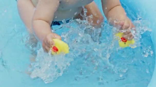 Childs mãos com patos de borracha amarela espirra água durante a natação na piscina ao ar livre no verão. Menino a divertir-se. Conceito de estilo de vida saudável, família, lazer no verão. Movimento lento . — Vídeo de Stock