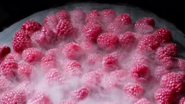 Reife gekühlte rote Himbeeren mit Trockeneisdampf isoliert auf dunklem Hintergrund. Ernährung, Vitamine, Antioxidantien. Blick auf köstliches Dessert. — Stockvideo