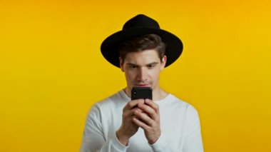 Yakışıklı bir adam cep telefonundan mutlu bir haber alır. Adam şaşkınlık ve sevinçle kendinden geçmiş. Kazandı ve sevindi. Teknoloji, başarı, zafer, mutluluk kavramı.