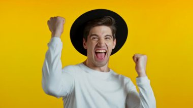 Evet, kazanan jest. Şaşırmış Avrupalı hippi adam şok oldu. Şapkalı yakışıklı adam sarı arka planda kameraya şaşırdı.