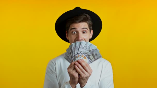 Εκπληκτική χαρούμενος ενθουσιασμένος άνθρωπος δείχνει χρήματα - ΗΠΑ χαρτονομίσματα σε δολάρια σε κίτρινο τοίχο. Σύμβολο επιτυχίας, κέρδους, νίκης. — Αρχείο Βίντεο