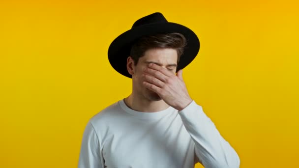 Frustrated european man in white wear and hat over yellow wall background. Guy is tired, bored of work or studying, he disappointed, helpless — Stock Video