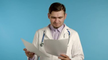 Mavi arka planda izole edilmiş dosyaları tutan profesyonel ceketli tatmin olmuş bir adam. Doktor 'a sakal ve steteskopla teşhis koymayı onaylıyor.. 