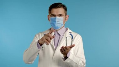 Koruyucu maskeli doktor ellerine antiseptik uyguluyor ve temiz ve steril olduğunu gösteriyor. Virüs konseptini durdur, bakteri koruması.