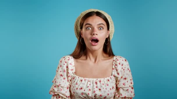Amazed european woman shocked, saying WOW. Pretty girl in straw hat surprised to camera over blue background. — Stock Video