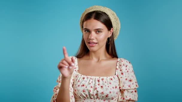 Hermosa mujer en vestido floral sosteniendo el dedo en sus labios sobre fondo azul. Gesto de silencio, secreto, silencio. De cerca.. — Vídeos de Stock