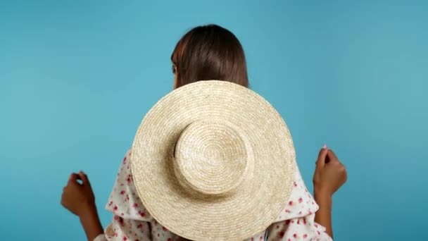 Unrecognizable woman with straw hat dancing with her back to camera on blue background. Trendy girl. Party, happiness, freedom, youth concept. — Stock Video