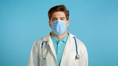 Profesyonel medikal beyaz önlüklü ve maskeli genç doktor yüzünü ölümcül hayal kırıklığından ve başarısızlıktan eliyle kapatıyor. Depresyondaki kayıp adam. Drama, duygu konsepti.