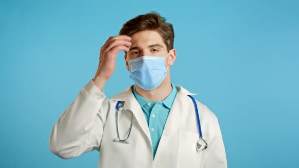 Frustrerad läkare man i vitt slitage och mask över blå vägg bakgrund. Doc är trött, uttråkad av arbete, han besviken, hjälplös — Stockvideo