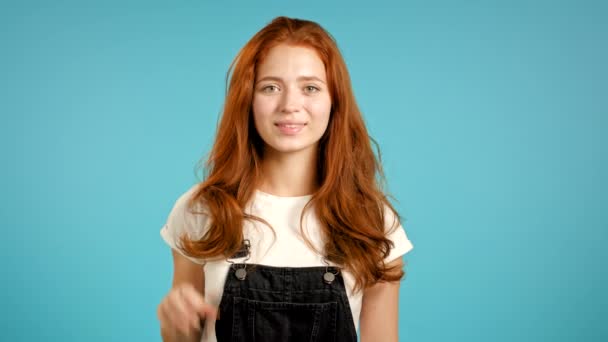 Leuke vrouw met een goed teken op een blauwe achtergrond. Positief jong meisje glimlacht naar de camera met ok. Winnaar. Succes. Lichaamstaal. — Stockvideo