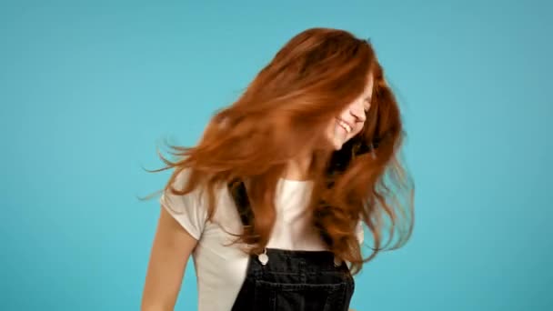 Mooie vrouw die energiek en actief danst op een blauwe studio achtergrond. Schattig meisje in het zwart over het algemeen. Feest, geluk, vrijheid, jeugdconcept. — Stockvideo